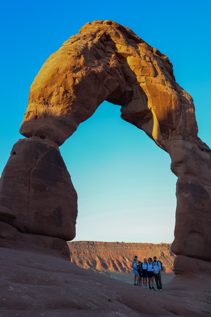 Delicate Arch in Arches National Park, a massive sandstone arch with people at its base for scale.